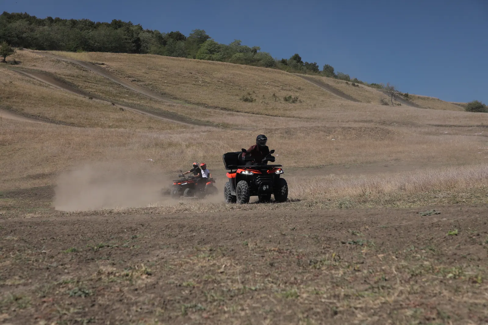 Două ATV-uri apropiindu-se pe un traseu prăfuit printre dealuri